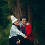 Happy couple sitting together in a green park, enjoying a joyful moment filled with love and affection.