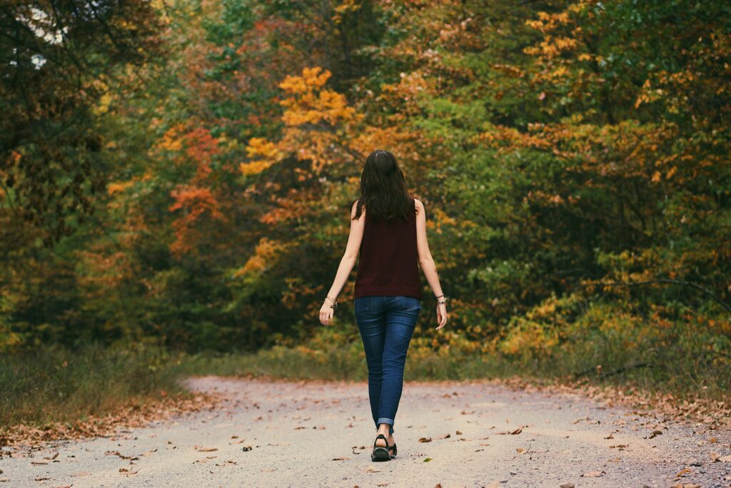 pexels-photo-906106-906106 A young woman walks down a colorful autumn forest path, surrounded by vibrant leaves.